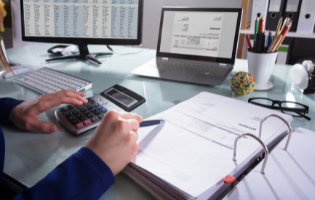 Hands in Front of Calculator, Notebooks and Computer