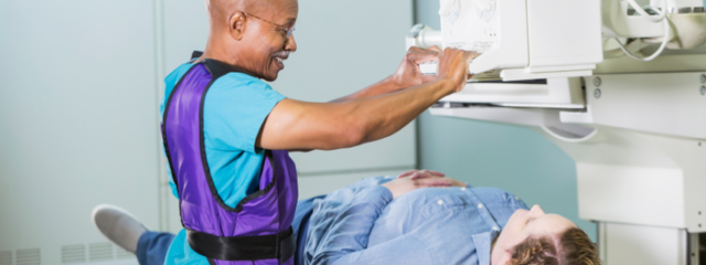 Man Lowering Imaging Machine onto Female Patient