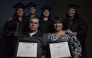 Latino family smiling and holding college degrees